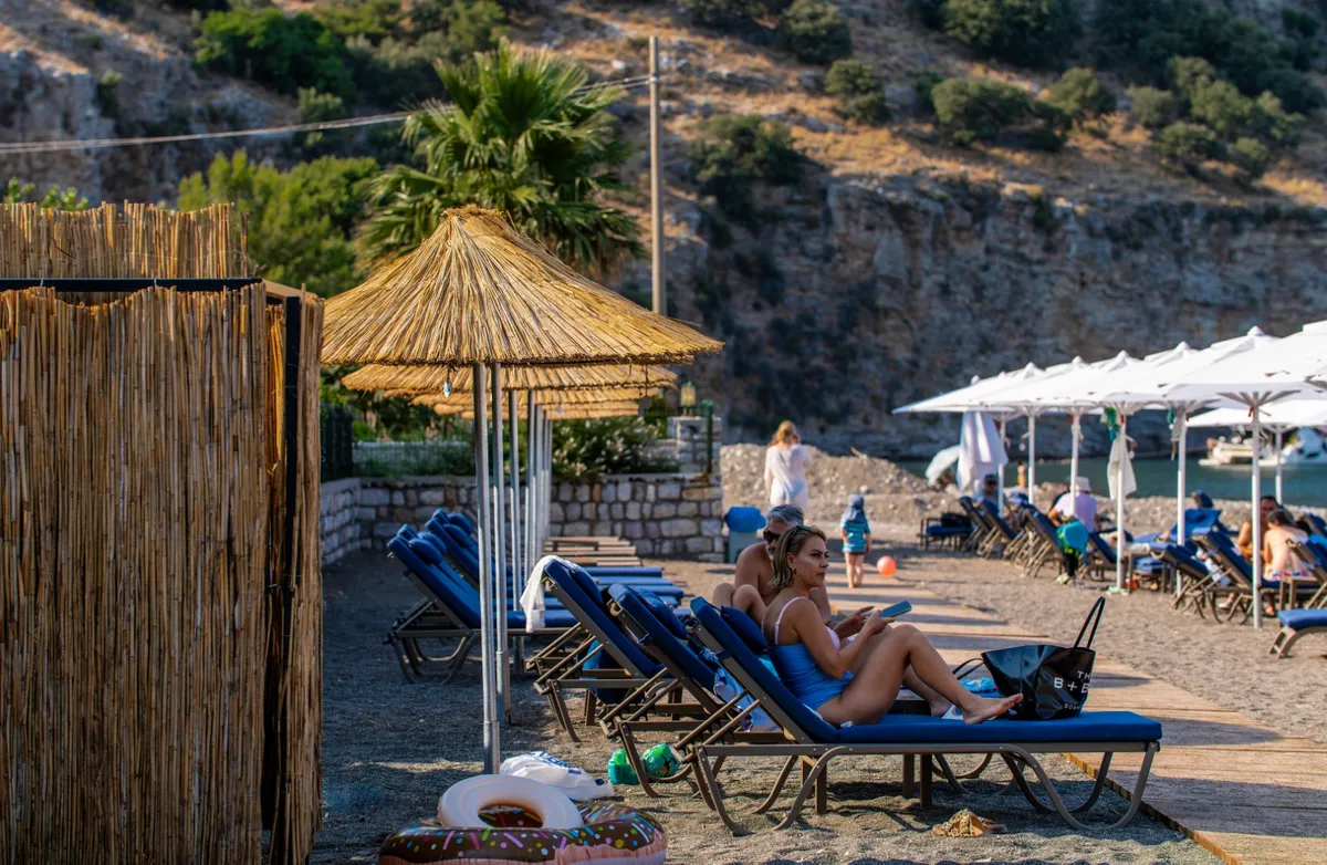 Hasır şemsiyeler ve lacivert şezlonglarla Vita Beach plajı